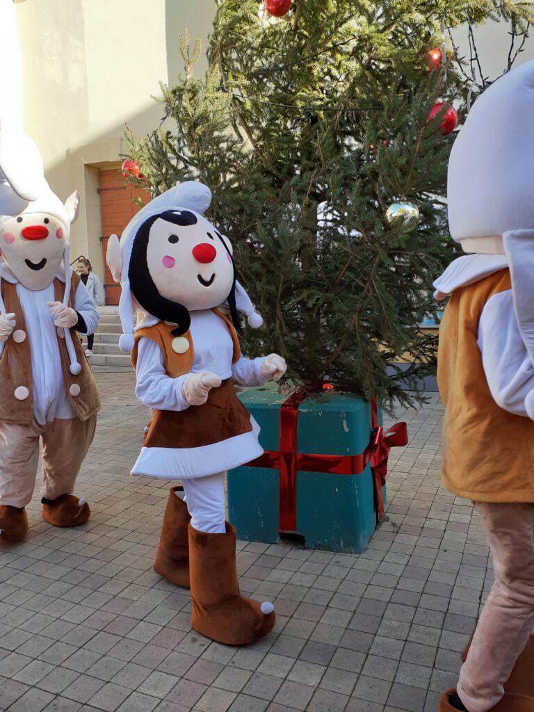 Verkleidete Darsteller auf dem Weihnachtsmarkt, die um einen Christbaum tanzen